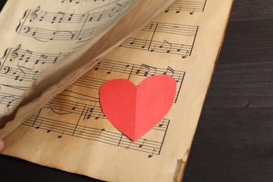 Paper heart and musical notes on black background, closeup