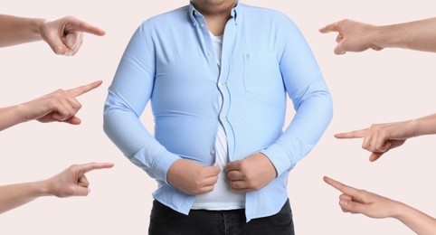 People pointing at overweight man trying to button up tight shirt on white background, banner design. Stop body shaming