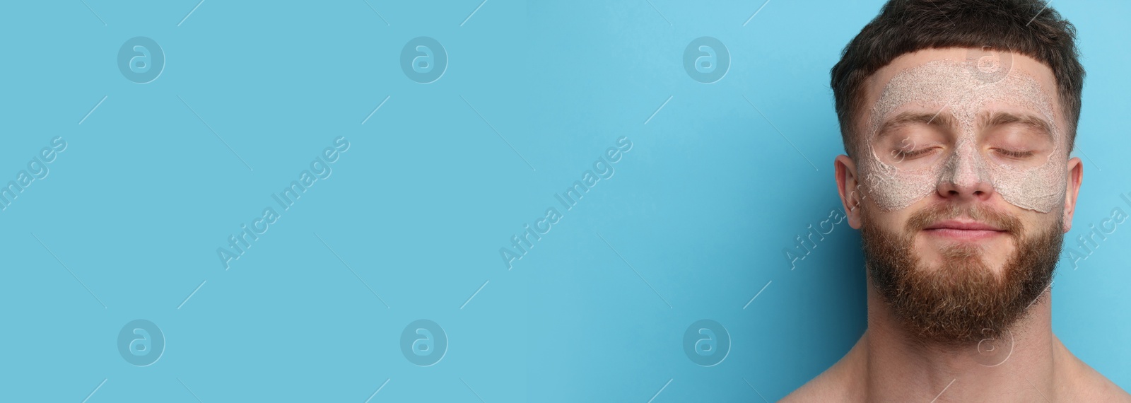 Image of Young man with mask on his face against light blue background. Banner design with space for text. Skin care