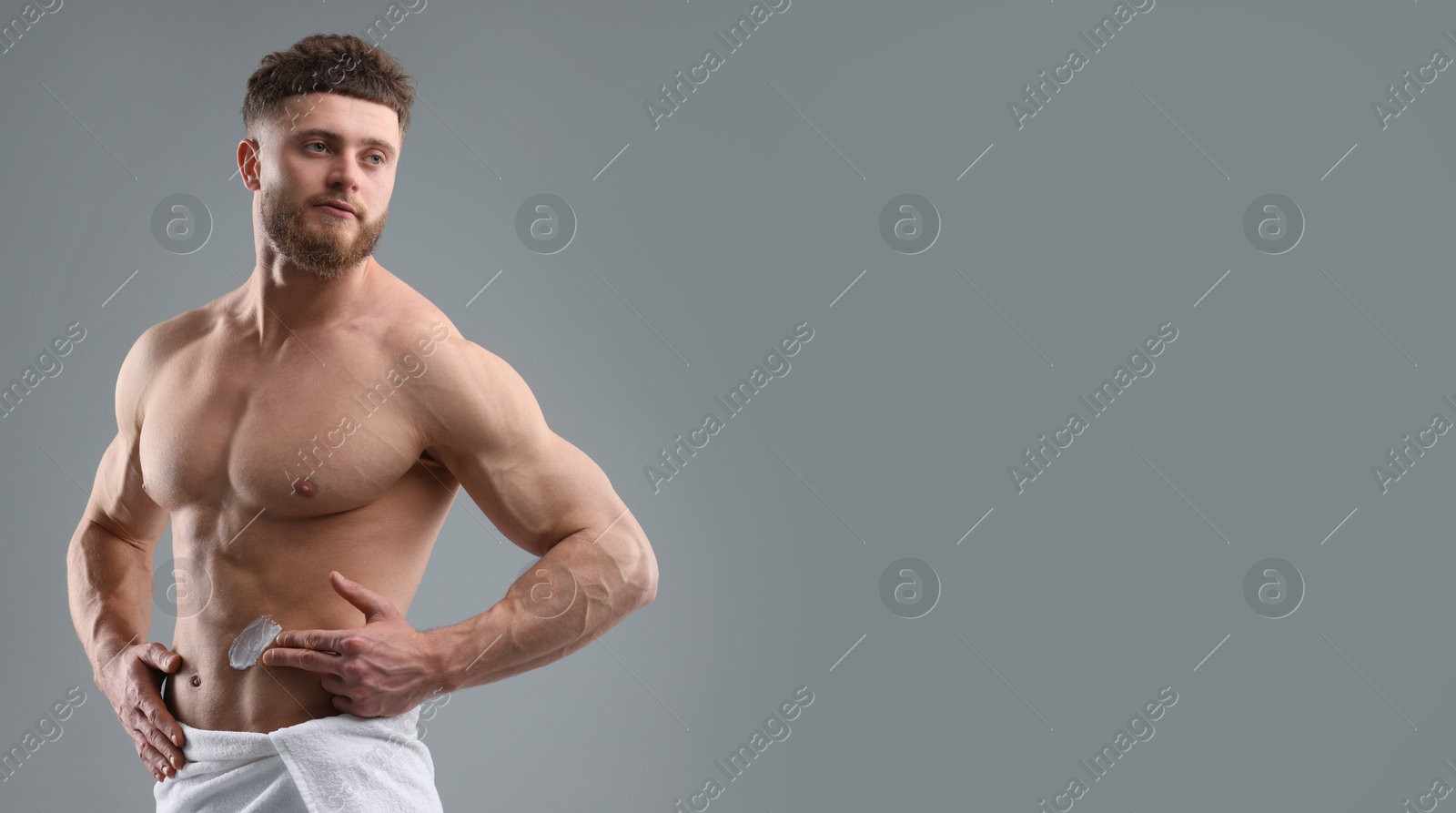 Image of Young man applying cream on skin against grey background. Banner design with space for text. Body care