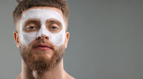 Young man with mask on his face against grey background. Banner design with space for text. Skin care