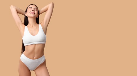 Beautiful woman with smooth skin in underwear on dark beige background. Banner design with space for text. Body care