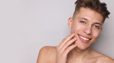 Young man with cream on his face against light grey background. Banner design with space for text. Skin care