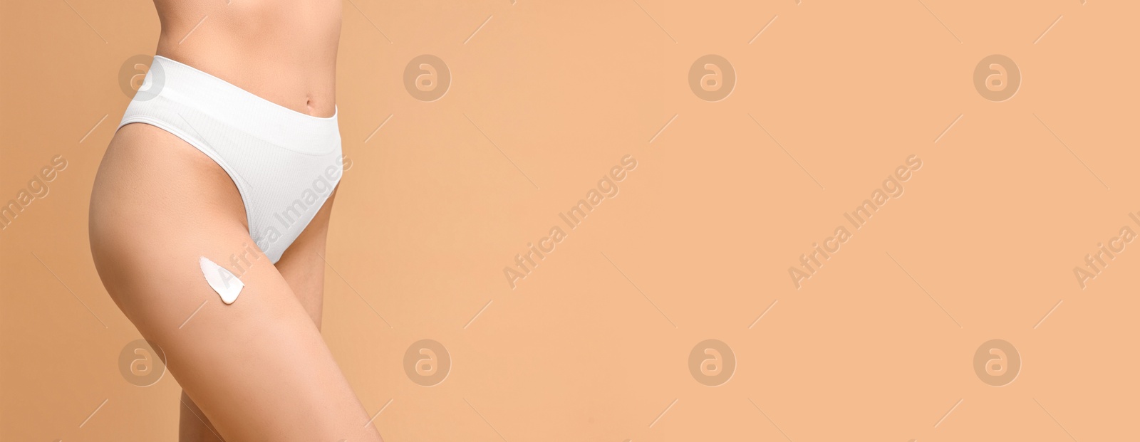 Image of Woman with cream on skin against dark beige background, closeup. Banner design with space for text. Body care