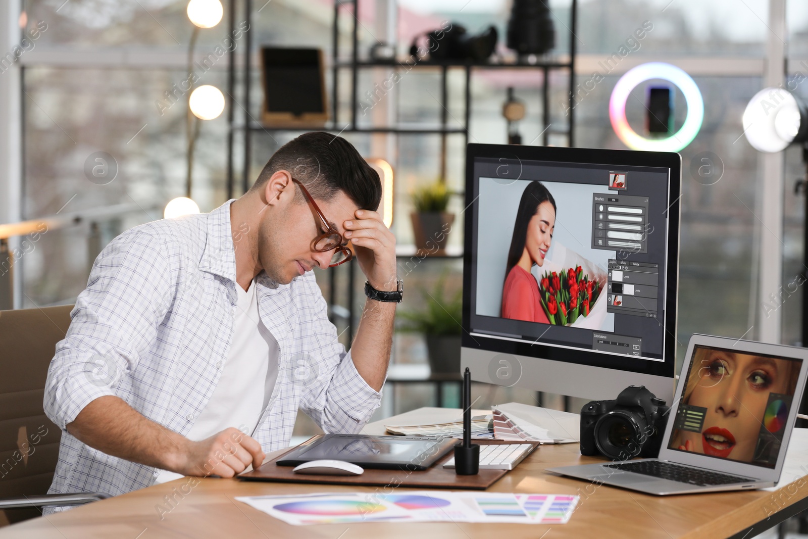 Photo of Tired retoucher at table with modern computer in office