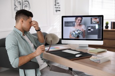 Tired retoucher at workplace with computer in office