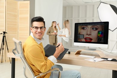 Photo of Professional retoucher working with graphic tablet at desk in photo studio