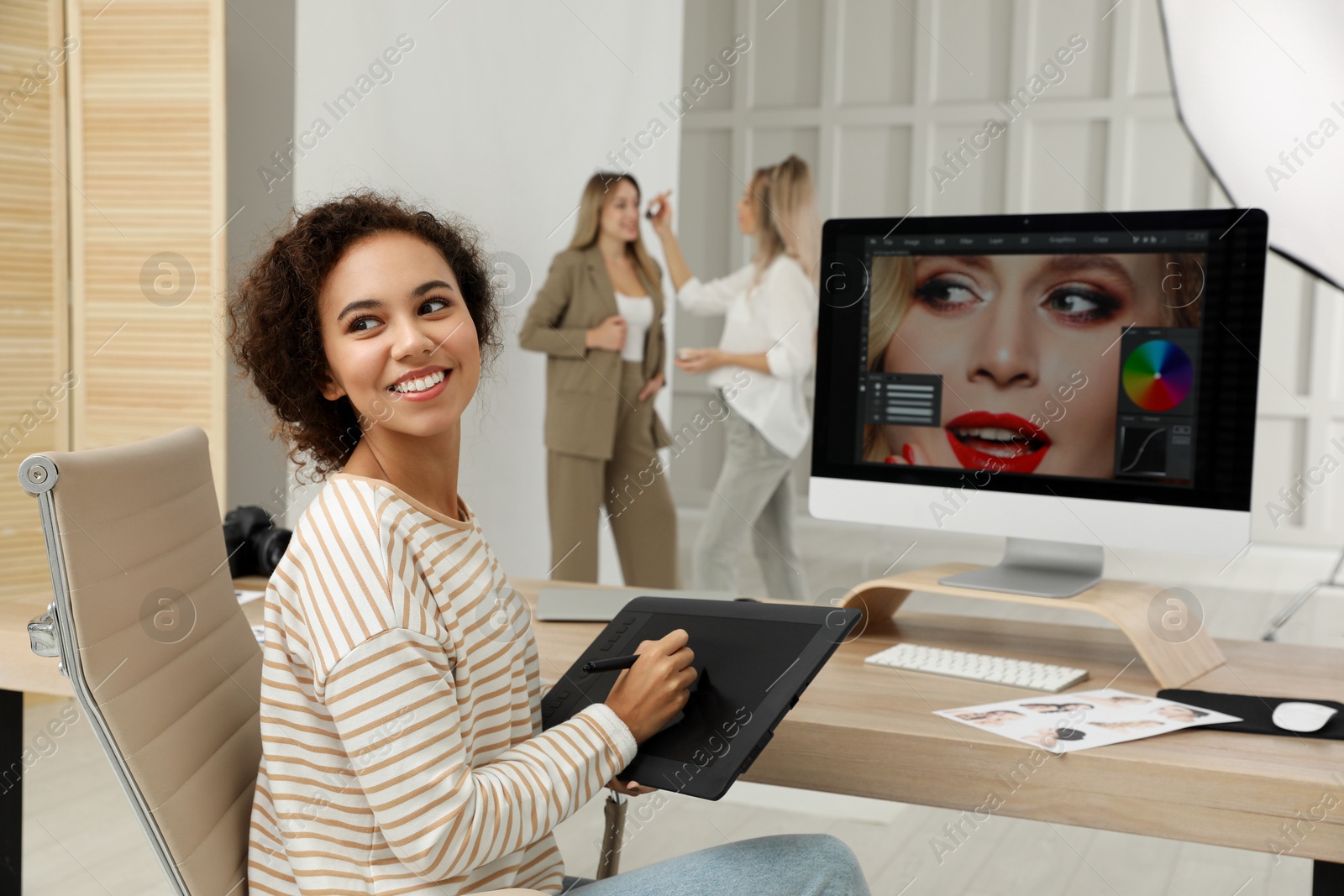 Photo of Professional African American retoucher working with graphic tablet at desk in photo studio