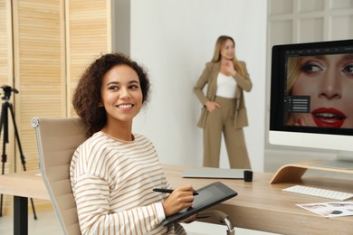 Photo of Professional African American retoucher working with graphic tablet at desk in photo studio