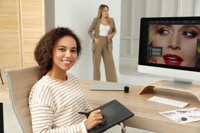 Photo of Professional African American retoucher working with graphic tablet at desk in photo studio