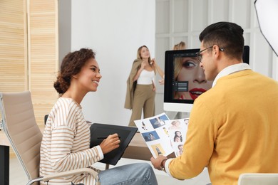 Photo of Professional retoucher with colleague working at desk in photo studio