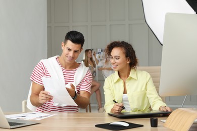 Photo of Professional retoucher with colleague working at desk in photo studio