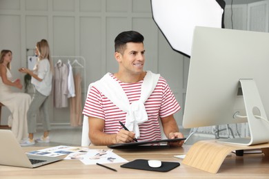 Photo of Professional retoucher working with graphic tablet at desk in photo studio