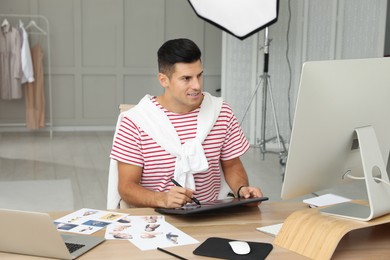 Photo of Professional retoucher working with graphic tablet at desk in photo studio