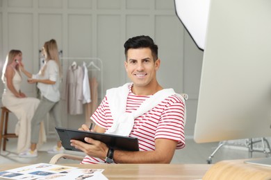 Photo of Professional retoucher working with graphic tablet at desk in photo studio