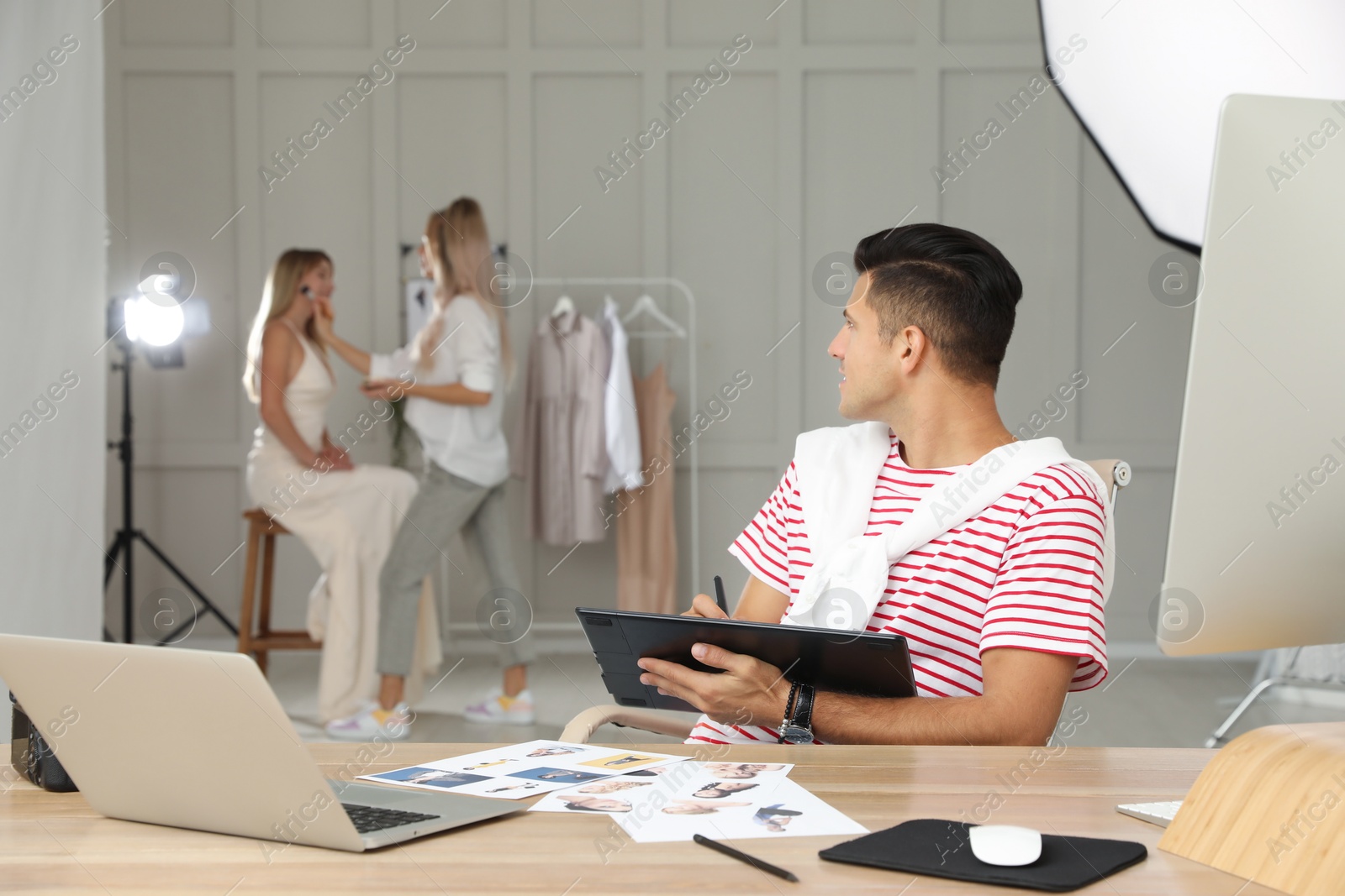 Photo of Professional retoucher working with graphic tablet at desk in photo studio