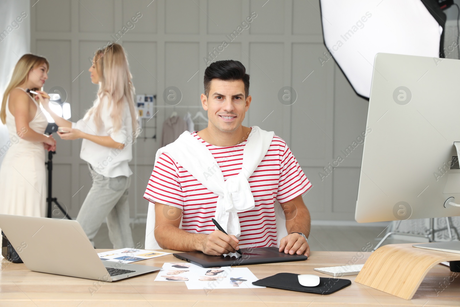 Photo of Professional retoucher working with graphic tablet at desk in photo studio