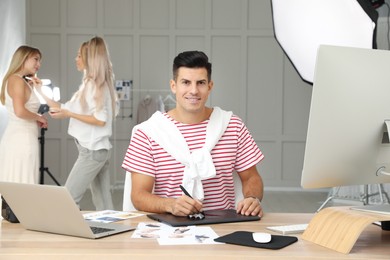 Photo of Professional retoucher working with graphic tablet at desk in photo studio