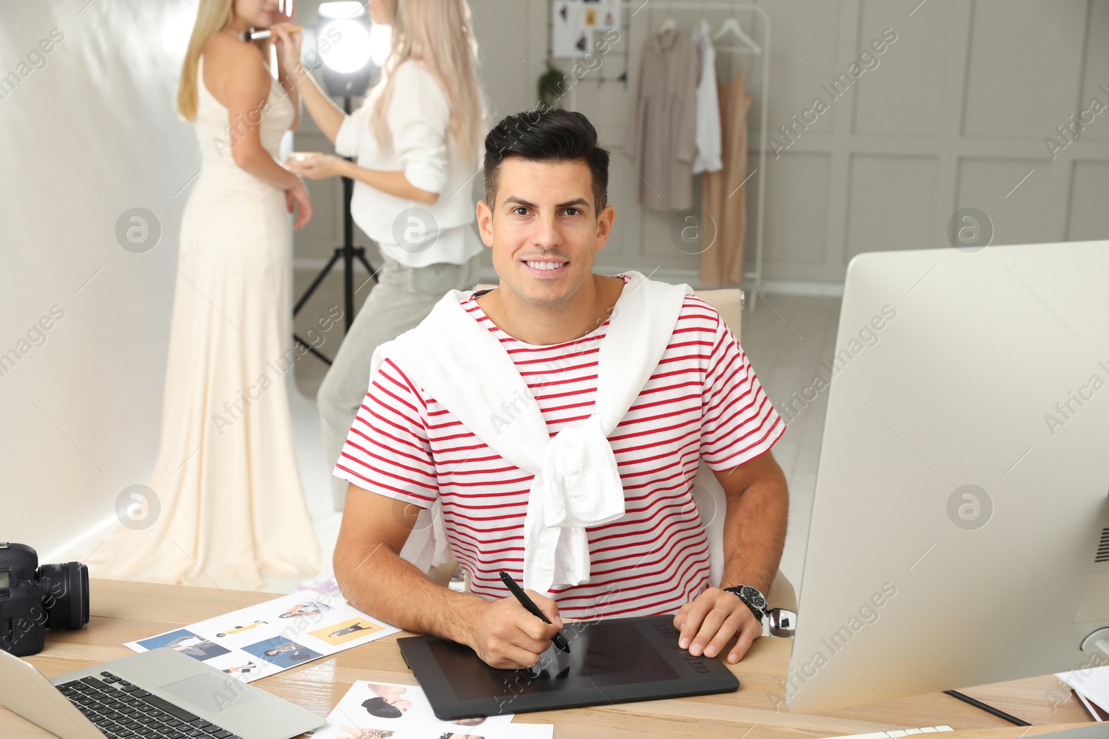 Photo of Professional retoucher working with graphic tablet at desk in photo studio