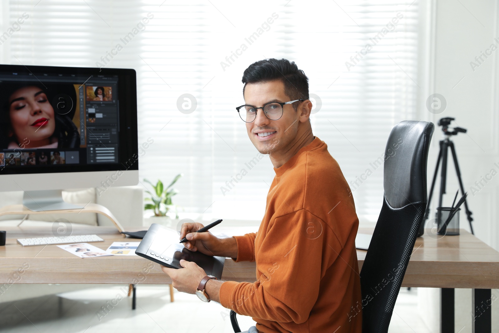 Photo of Professional retoucher working with graphic tablet at desk in office