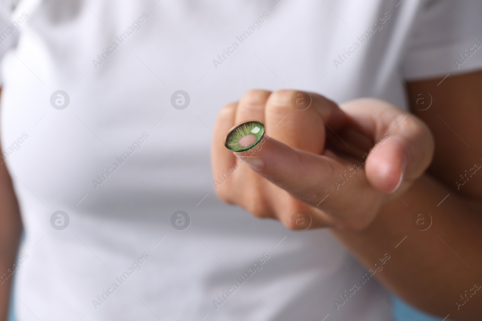 Photo of Woman holding color contact lens, closeup view