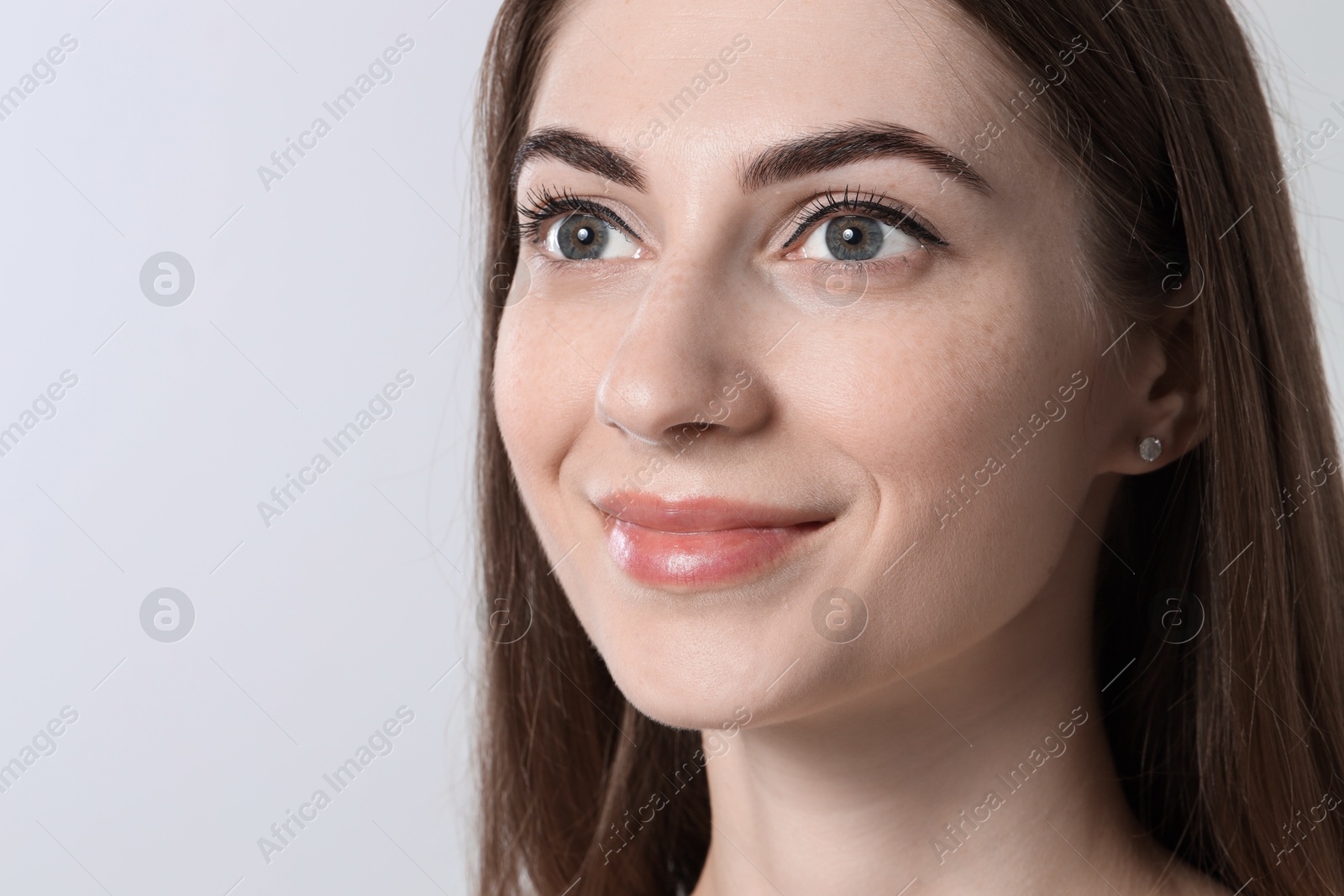 Photo of Beautiful young woman after henna eyebrows dyeing on light background