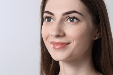 Photo of Beautiful young woman after henna eyebrows dyeing on light background