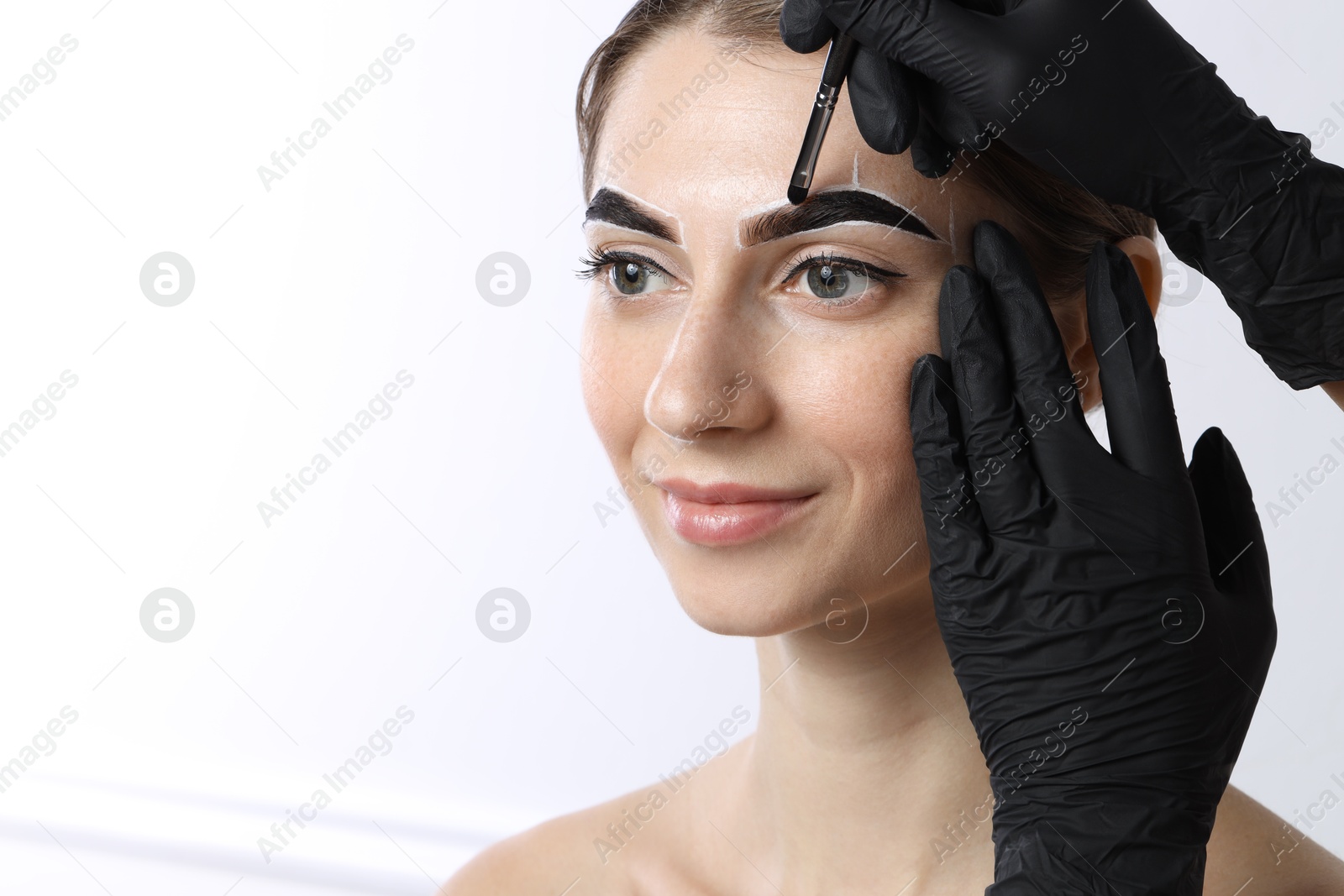 Photo of Young woman undergoing henna eyebrows dyeing on white background, closeup. Space for text