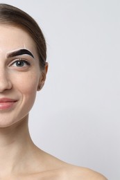 Photo of Young woman during henna eyebrows dyeing procedure on light background, closeup