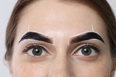 Photo of Young woman during henna eyebrows dyeing procedure on light background, closeup