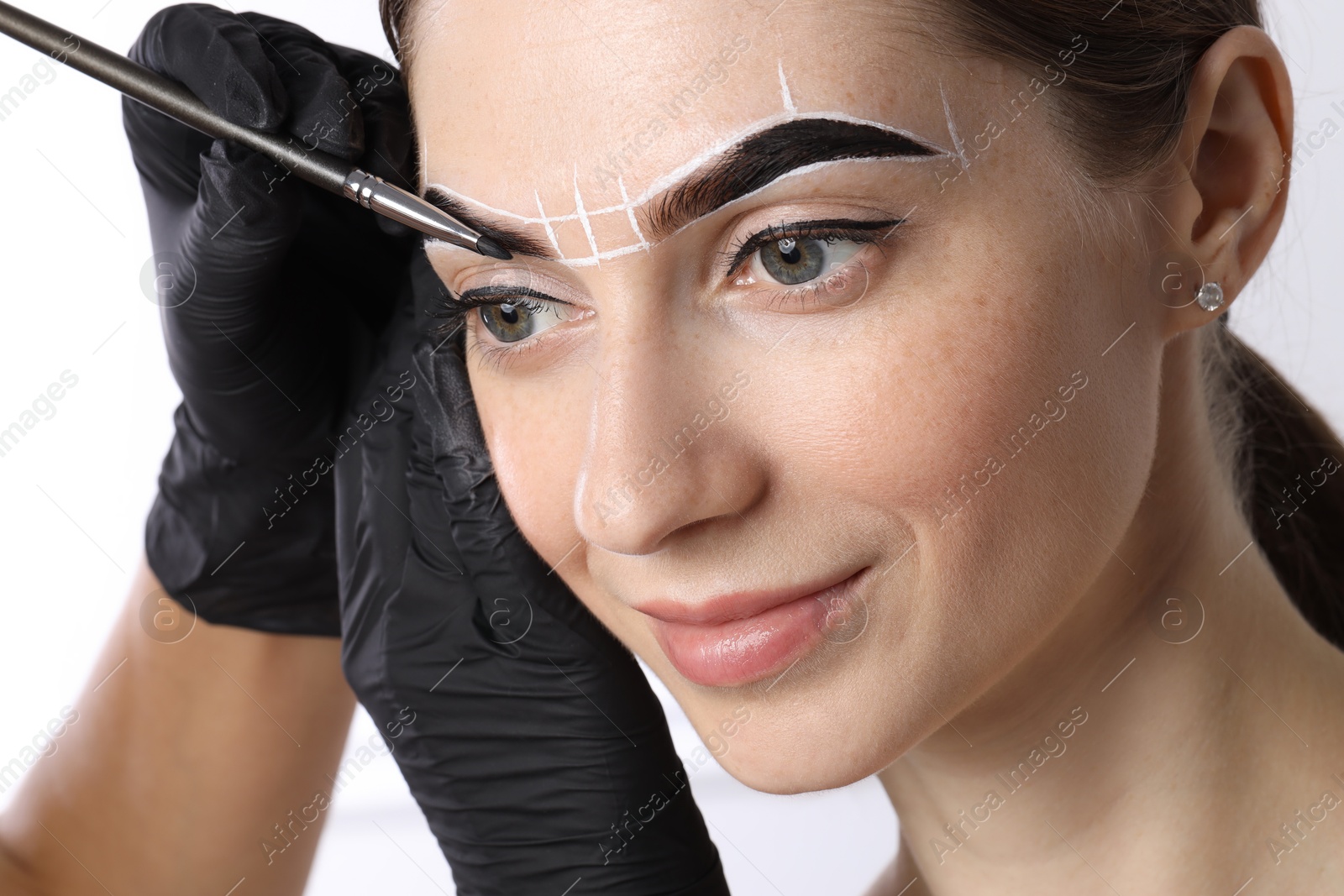 Photo of Young woman undergoing henna eyebrows dyeing procedure on light background, closeup