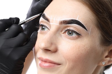 Photo of Young woman undergoing henna eyebrows dyeing procedure on light background, closeup