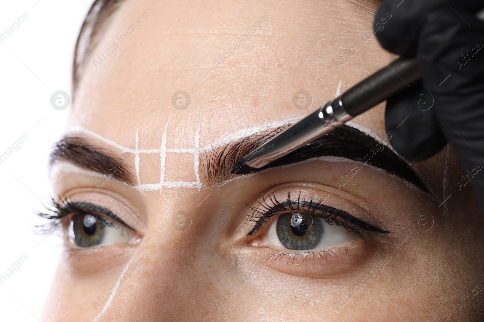 Photo of Young woman undergoing henna eyebrows dyeing on light background, closeup