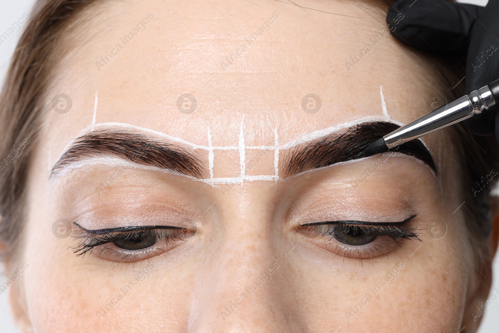 Photo of Young woman undergoing henna eyebrows dyeing procedure, closeup