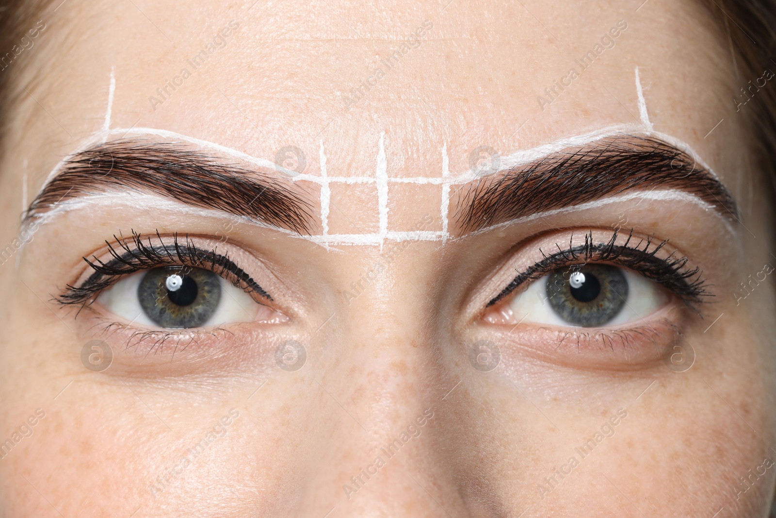 Photo of Young woman during henna eyebrows dyeing procedure, closeup