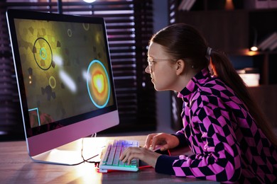 Photo of Girl playing video game with keyboard and mouse at table in dark room