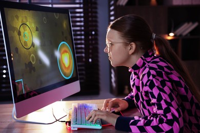 Photo of Girl playing video game with keyboard and mouse at table in dark room