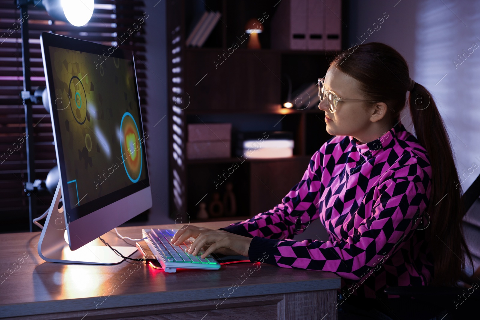 Photo of Girl playing video game with keyboard at table indoors