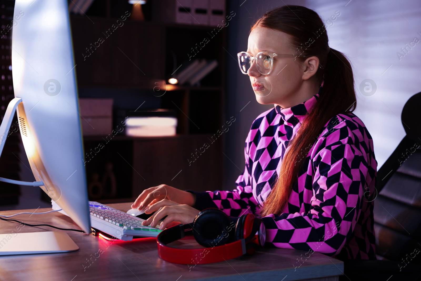 Photo of Girl playing video game with keyboard and mouse at table indoors