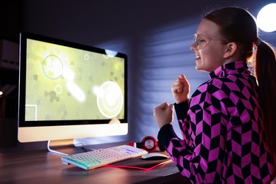 Photo of Happy girl playing video game with keyboard at table indoors