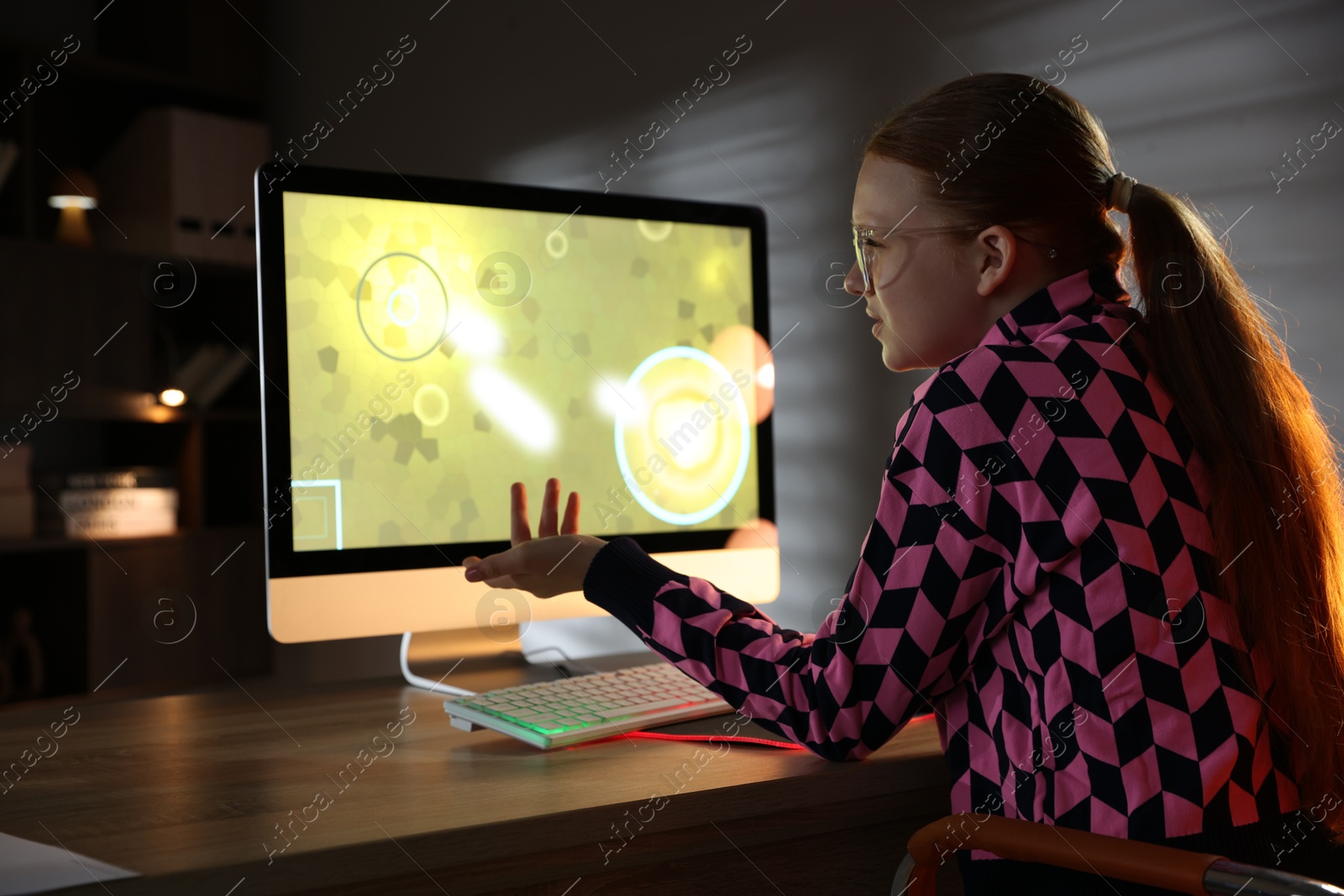 Photo of Girl playing video game with keyboard at table indoors