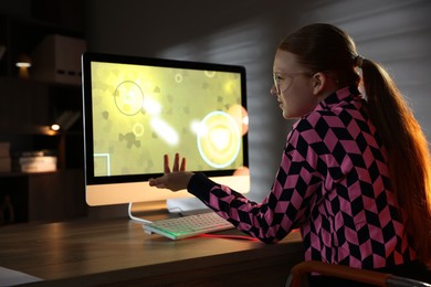 Girl playing video game with keyboard at table indoors