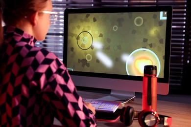 Girl playing video game with keyboard at table indoors, back view