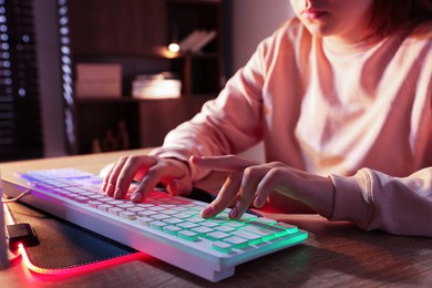 Photo of Girl using computer keyboard at wooden table indoors, closeup