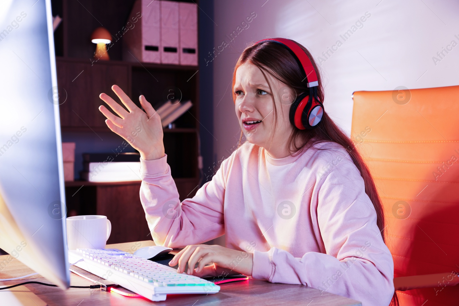 Photo of Emotional girl playing video game with keyboard and mouse at table indoors