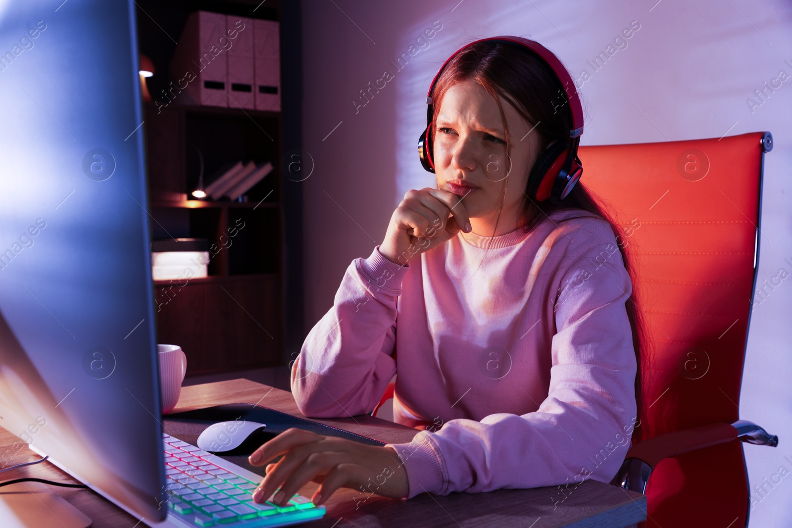 Photo of Emotional girl playing video game with keyboard and mouse at table indoors