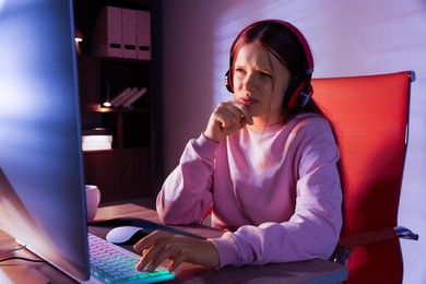 Photo of Emotional girl playing video game with keyboard and mouse at table indoors