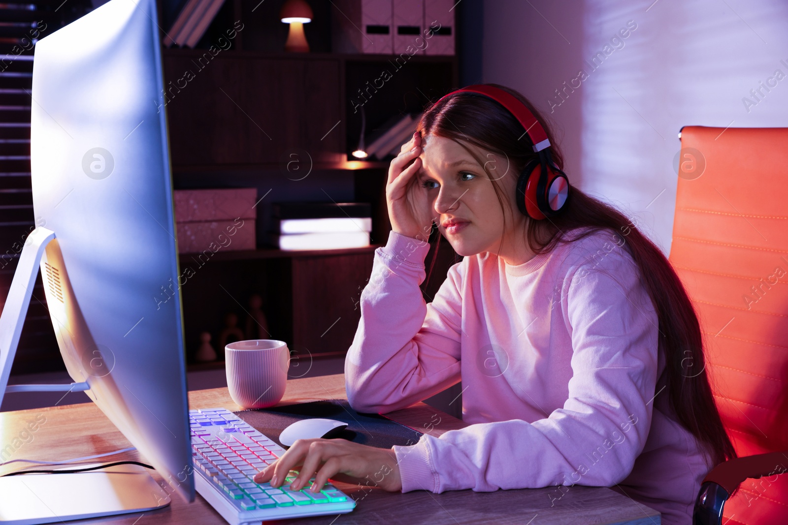 Photo of Emotional girl playing video game with keyboard and mouse at table indoors