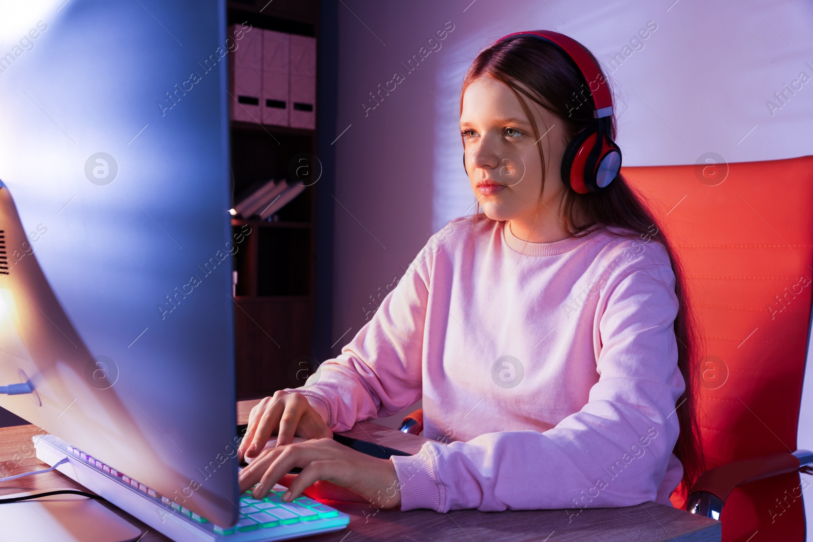 Photo of Girl in headphones using computer keyboard at table indoors