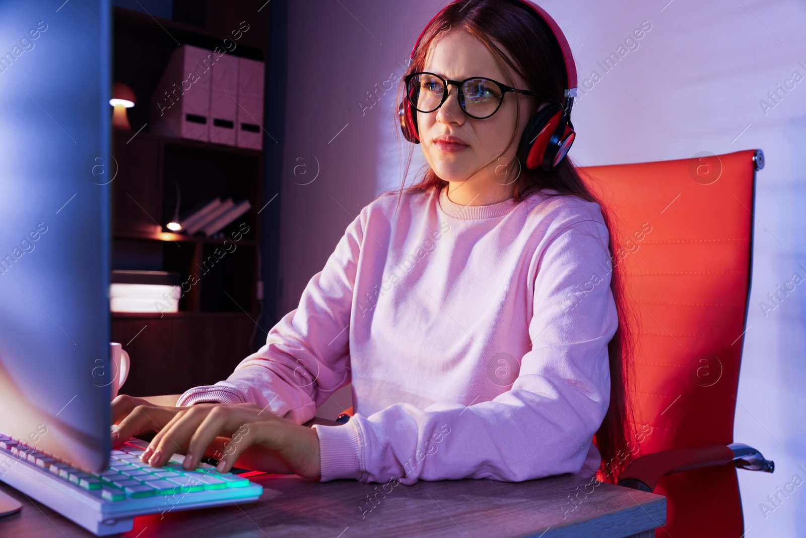 Photo of Girl in headphones using computer keyboard at table indoors